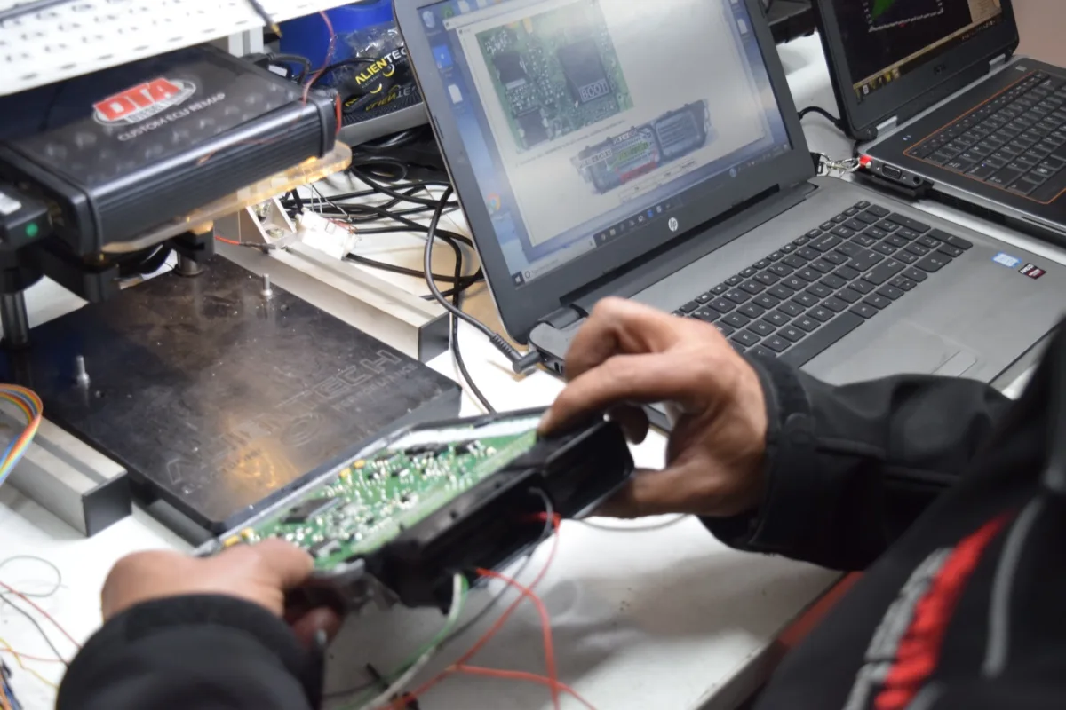Technician reading ECU data with ALIENTECH tool connected to laptop