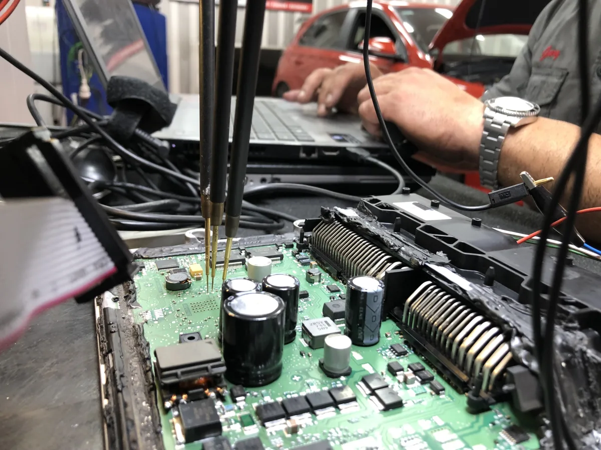 Technician with probe on ECU board at dyno workshop